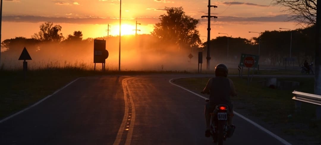 Mensajero en moto por una carretera al atardecer